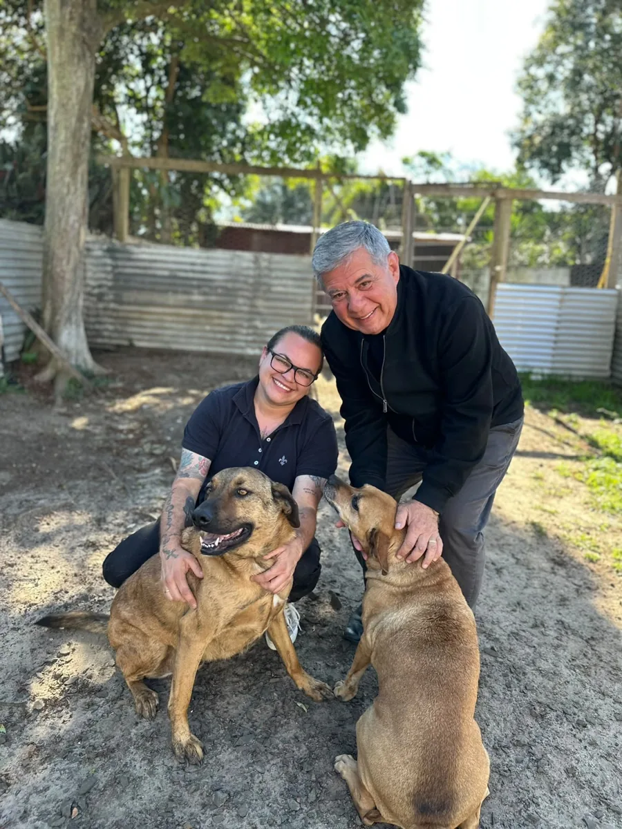 Vanessa Witiuk com dois cães e outra pessoa ao ar livre